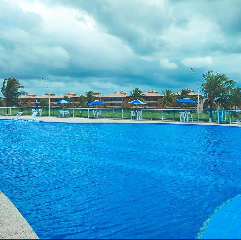 uma grande piscina azul com cadeiras e guarda-sóis em Resort Villa das águas praia do saco em Estância