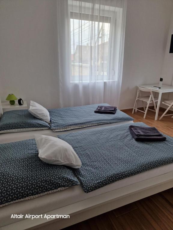 two twin beds in a bedroom with a window at Altair Airport Apartman in Vecsés