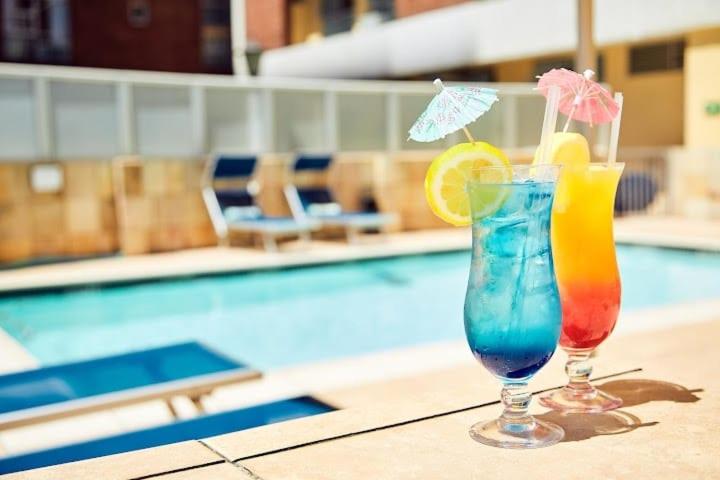 two cocktails sitting on a table next to a swimming pool at Oceanic Unit 122 - North Beach in Durban