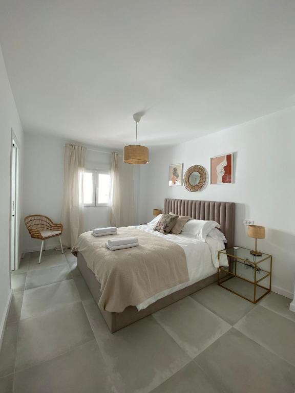 biała sypialnia z dużym łóżkiem i krzesłem w obiekcie Stylish Seaside 3 Bed Apartment with Terrace + Sea View w mieście Benalmádena