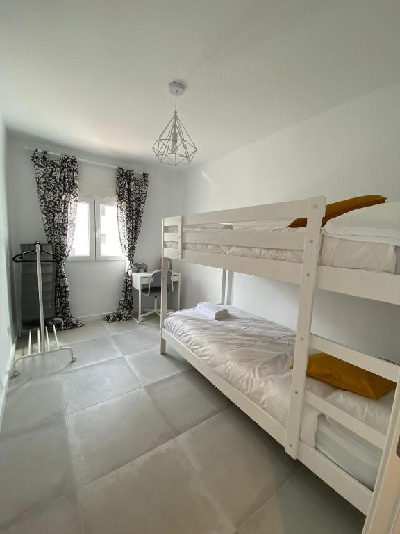 sypialnia z 2 łóżkami piętrowymi i podłogą wyłożoną kafelkami w obiekcie Stylish Seaside 3 Bed Apartment with Terrace + Sea View w mieście Benalmádena
