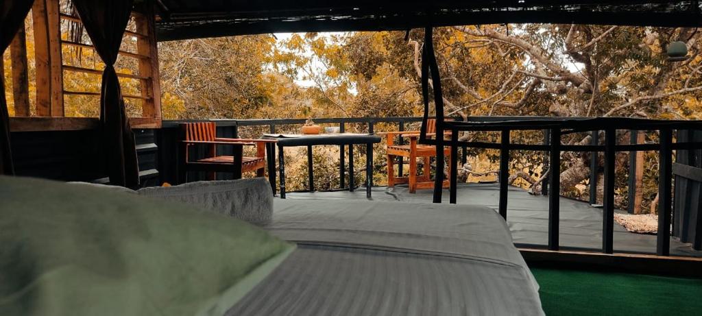 Bundala Levagamgoda的住宿－Jungle Cabin，门廊配有一张床,甲板配有桌子