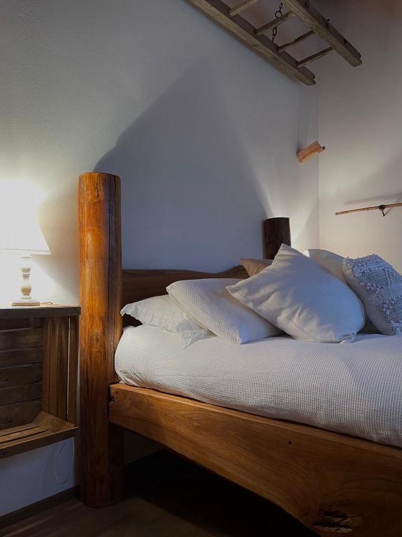 um quarto com uma cama de madeira e almofadas brancas em La Perla del Riso Melotti em Isola della Scala