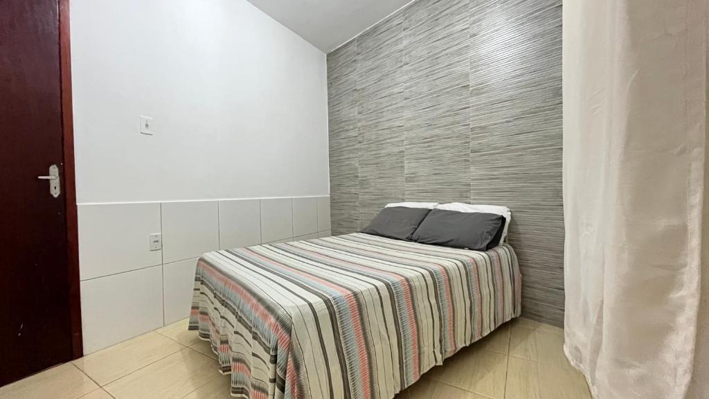 Habitación pequeña con cama con manta a rayas en Casa 1 na hospedagem seropedica Próximo a universidade en Seropédica