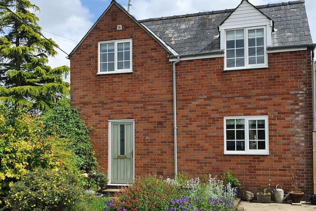 a red brick house with two windows and a door at Countryside 3 Bed Detached Cottage in Royal Wootton Bassett
