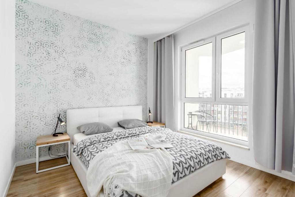 a white bedroom with a bed and a window at Chill Apartments Central Park in Warsaw