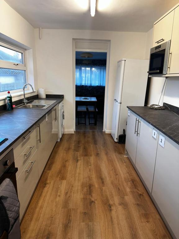 cocina con armarios blancos y suelo de madera en Stylish Town House - Modern double room - 3, en Parkside