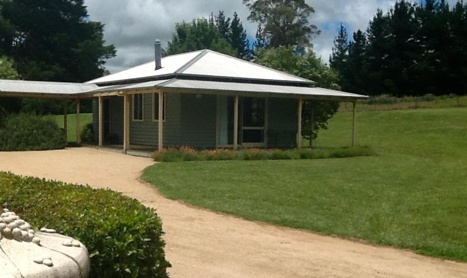 una pequeña casa verde con un patio de césped en Glen Waverly Farmstay, en Glen Innes