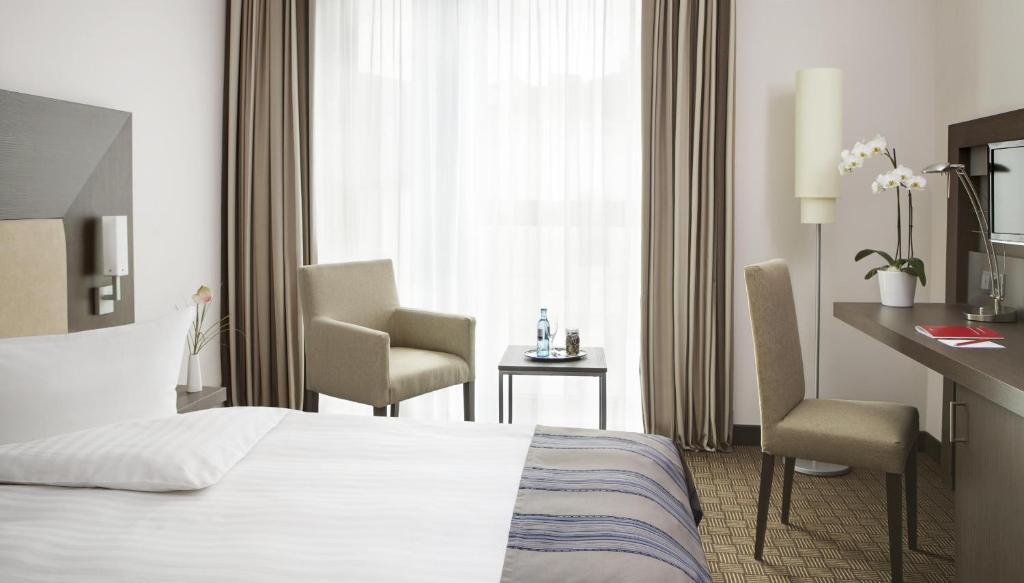 a hotel room with a bed and a desk and chairs at IntercityHotel Bonn in Bonn