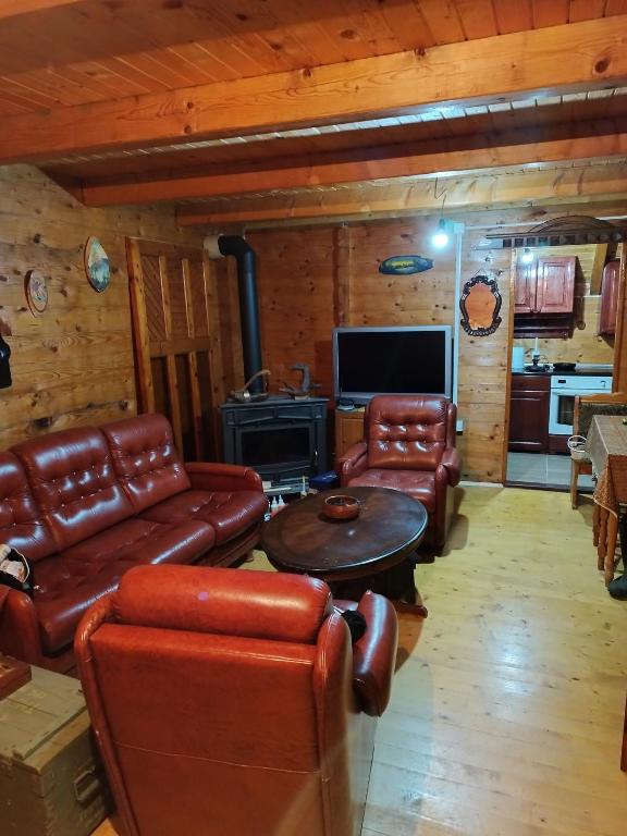 uma sala de estar com mobiliário de couro num chalé de madeira em Kuca u sumi em Bijelo Polje