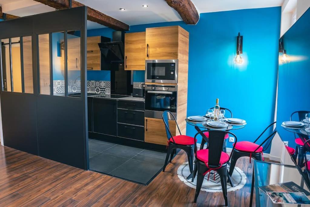 a kitchen with blue walls and a table with red chairs at Appartement climatisé avec garage au cœur du centre ancien in Sainte-Maxime