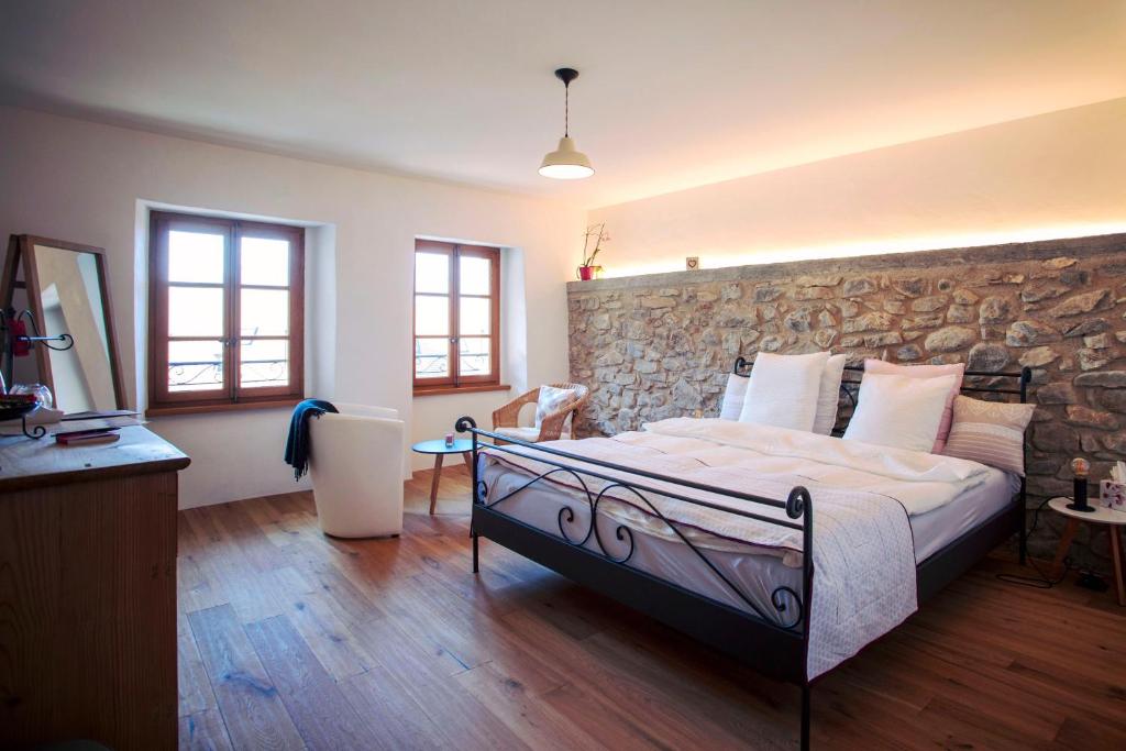 1 dormitorio con cama y pared de piedra en Aux Trois Soleils, en Chexbres