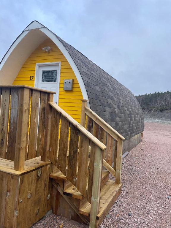 ein kleines gelbes Haus mit einer Holzterrasse in der Unterkunft Hillside Cottages in Bay Roberts