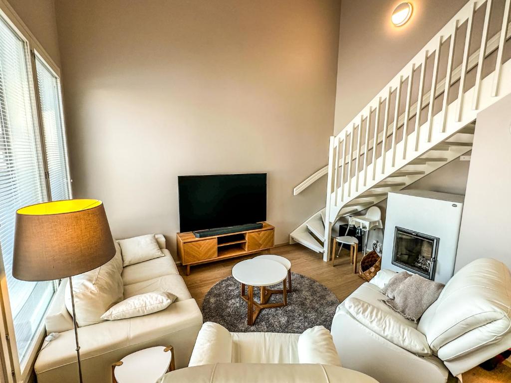 a living room with white furniture and a tv at Vuokatin kultaranta in Sotkamo