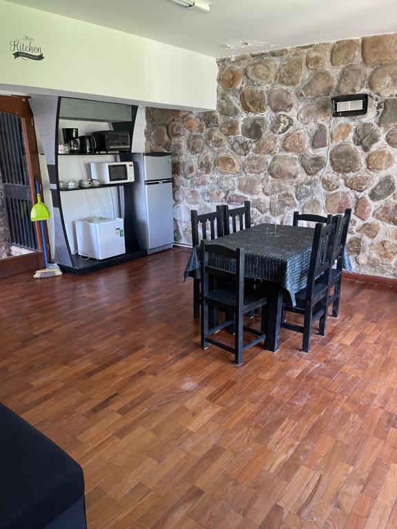 a dining room with a table and chairs and a stone wall at Departamento zona residencial CON PILETA in Salta