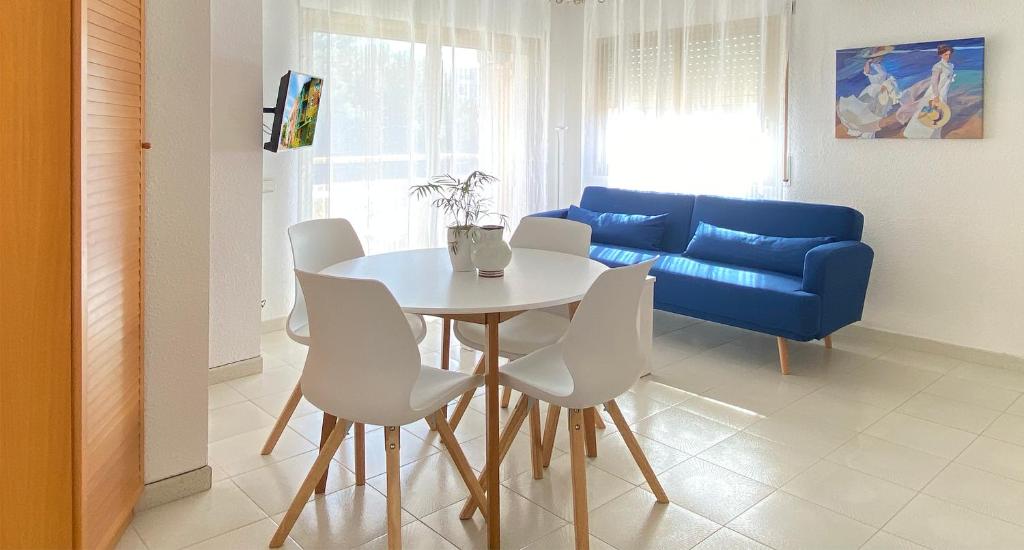 a living room with a table and a blue couch at Sunrise Studio Sorolla, 150 m de la playa in Miami Platja
