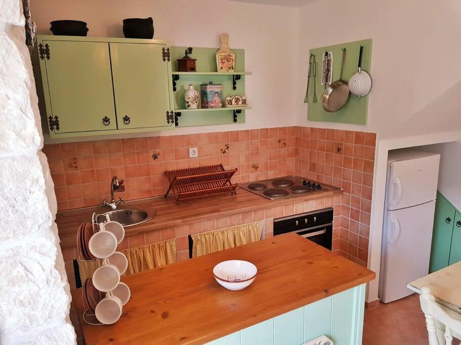 a kitchen with green cabinets and a wooden counter top at Vintage stone house ELDO in Podaspilje, Omiš in Omiš