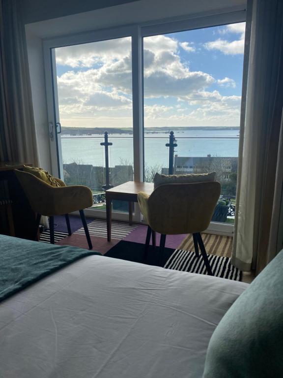 a bedroom with a bed and a view of the ocean at Flat 3, Murray Crescent House in Milford Haven