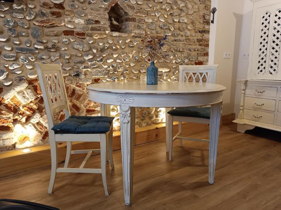 Biały stół i 2 krzesła w pokoju w obiekcie Le macareux, maison de pêcheur. w mieście Saint-Valéry-sur-Somme