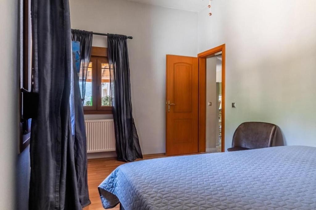 een slaapkamer met een bed, een stoel en een raam bij Villa Rose Garden in Panormos Skopelos