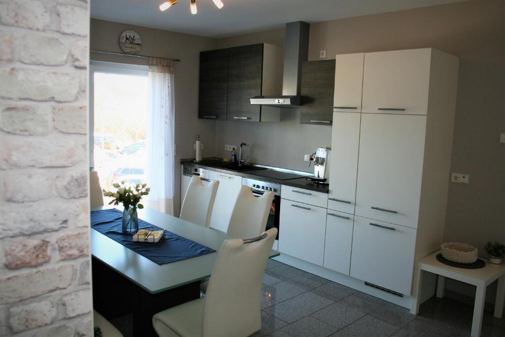 a kitchen with white cabinets and a table with white chairs at Ferienwohnung Hochwald 1 in Losheim
