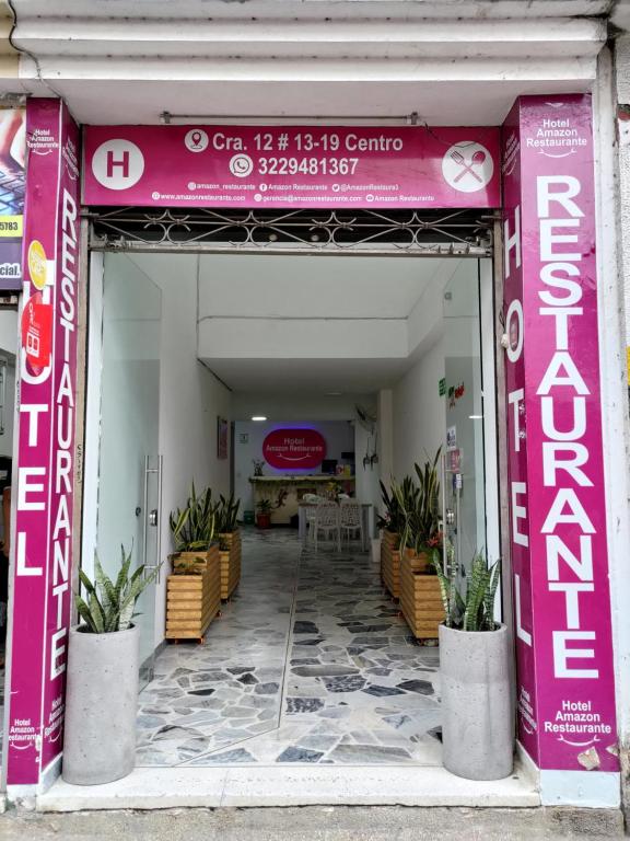 a pink entrance to a building with a table and chairs at Hotel Amazon in Florencia