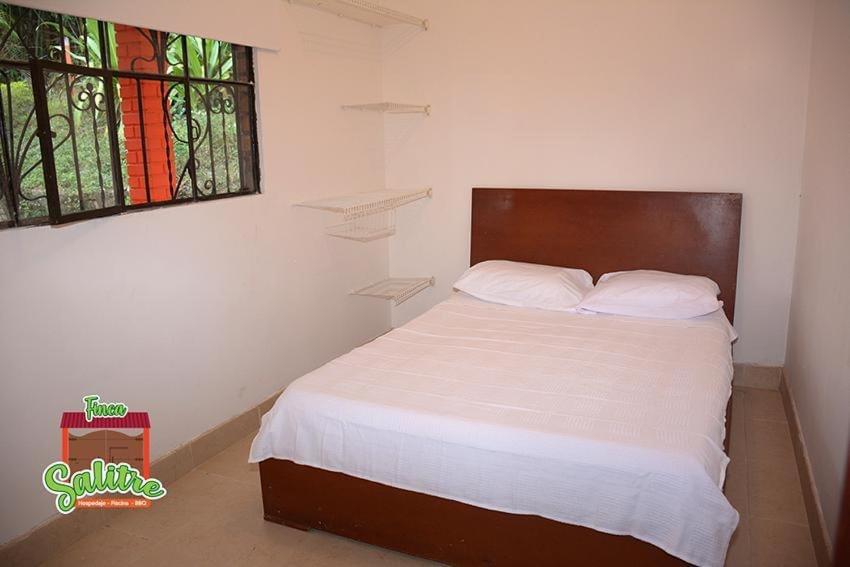 1 dormitorio con 1 cama con sábanas blancas y ventana en Finca Salitre, en Nimaima
