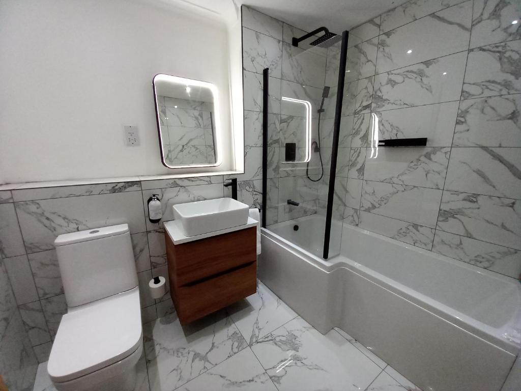 y baño con aseo, lavabo y ducha. en Ultra-Luxury City centre 2 bed apartment, with FREE parking, en Cardiff