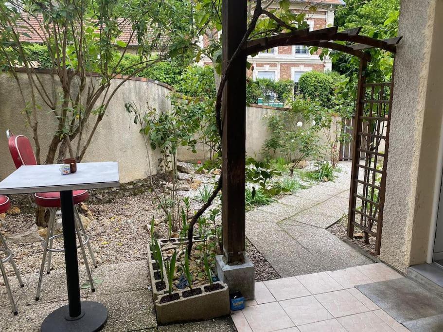 d'un jardin avec une table et un portail en bois. dans l'établissement Superbe appartement 2 chambres, à Évry-les-Châteaux