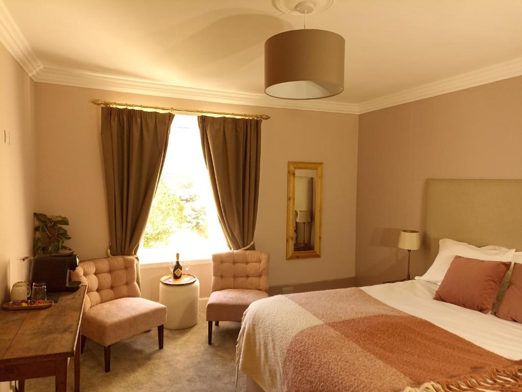 a bedroom with a bed and two chairs and a window at Abbeyfield B&B in Dufftown