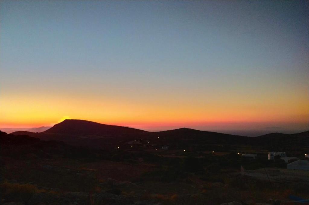 a sunset over a mountain with the sun setting behind it at Cycladic Villa in Amorgos Island (Maison Shiro) in Arkesíni