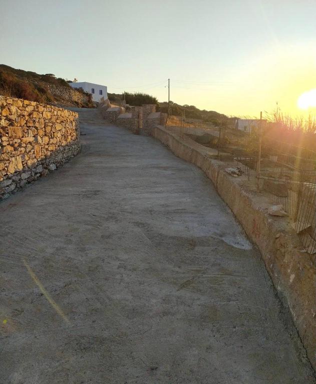 an empty road with a stone wall and the sunset at Cycladic Villa in Amorgos Island (Maison Shiro) in Arkesíni