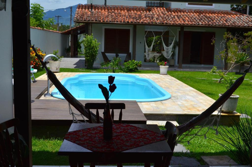 un patio trasero con piscina, mesa y sillas en Pousada Açai, en Paraty