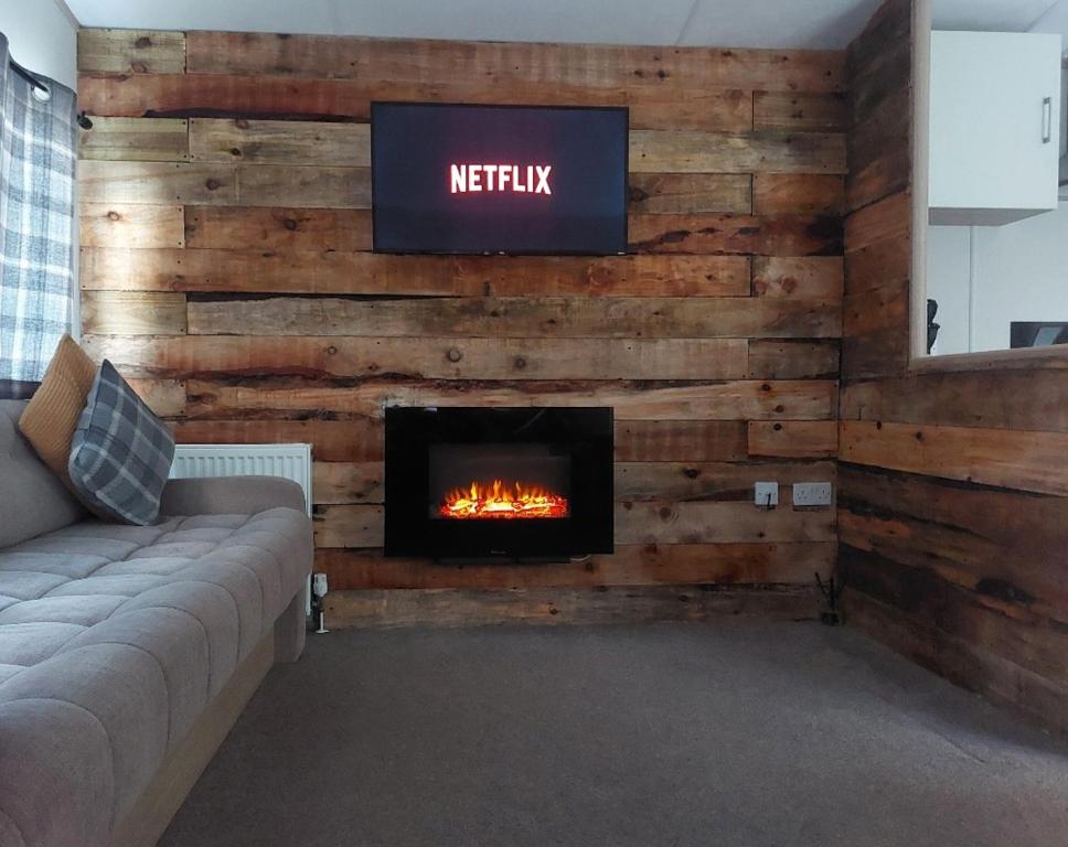 a living room with a fireplace and a tv on a wall at The Secret Wood in Swarland
