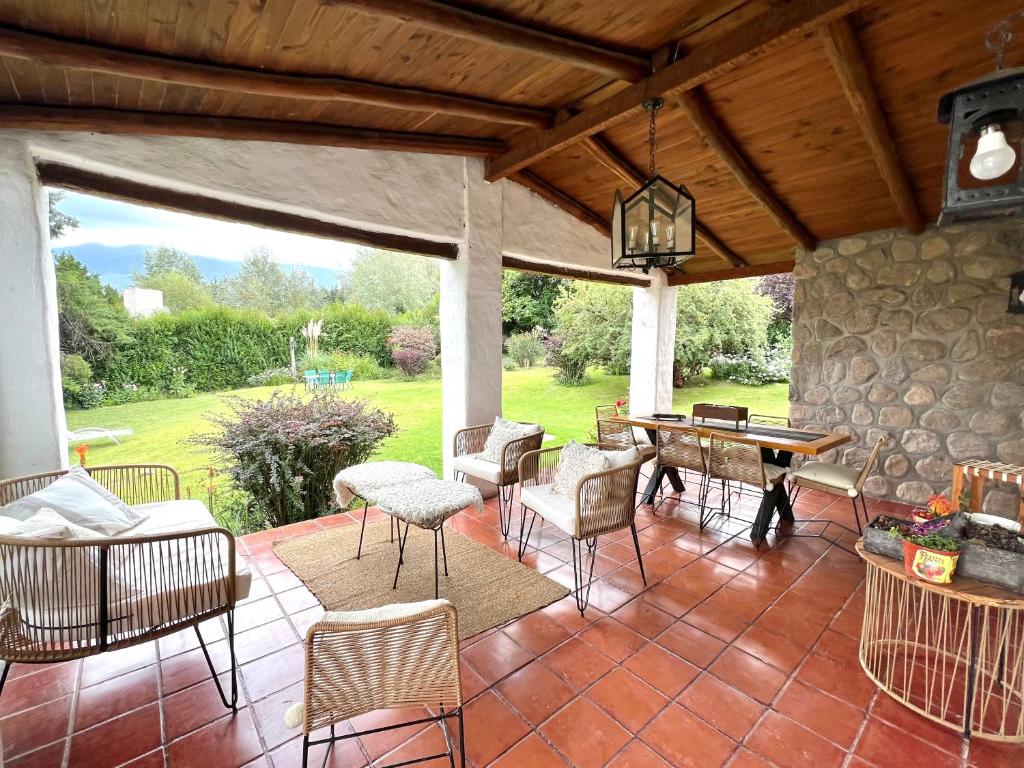 um pátio com cadeiras, uma mesa e uma parede de pedra em Casa divina temporaria en Tafí Del Valle ,pleno centro em Tafí del Valle