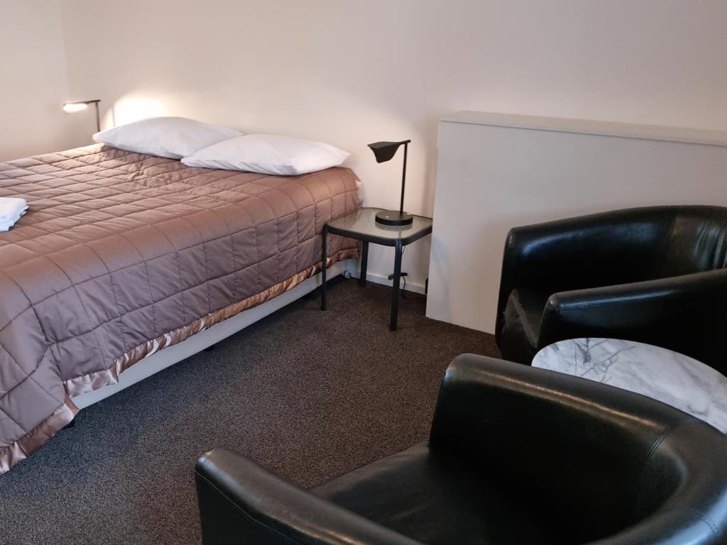 a hotel room with a bed and a chair at Stonehaven Motel in Whangarei