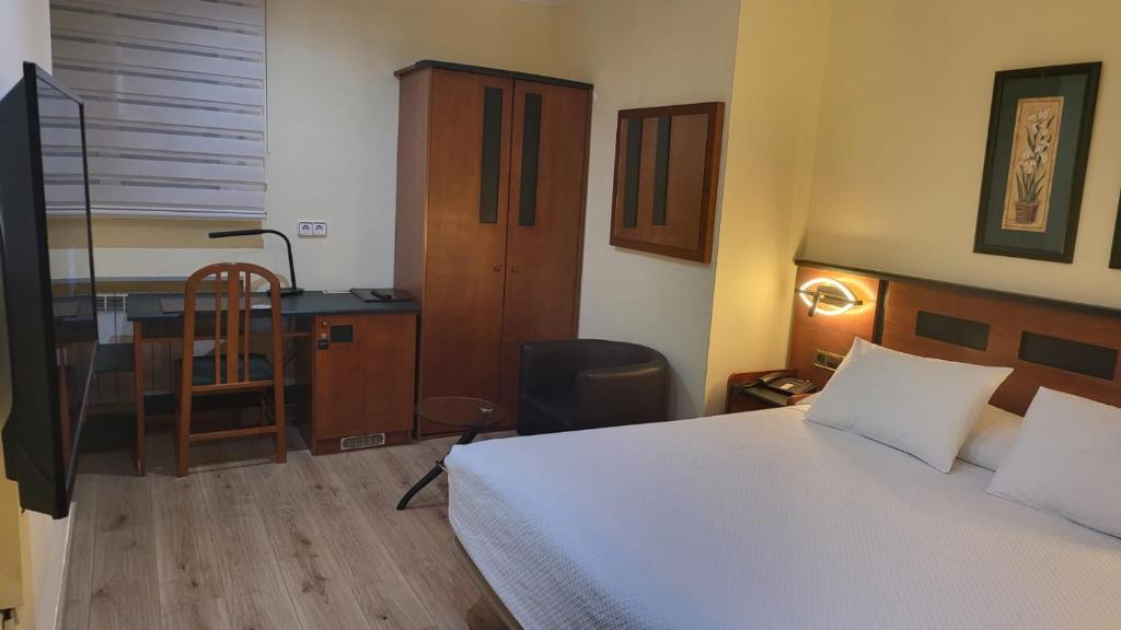 Habitación de hotel con cama, escritorio y escritorio. en Idh Angel, en Oviedo
