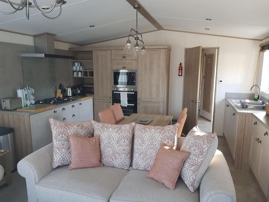 een woonkamer met een bank met kussens erop bij Modern, stylish holiday home in Bembridge
