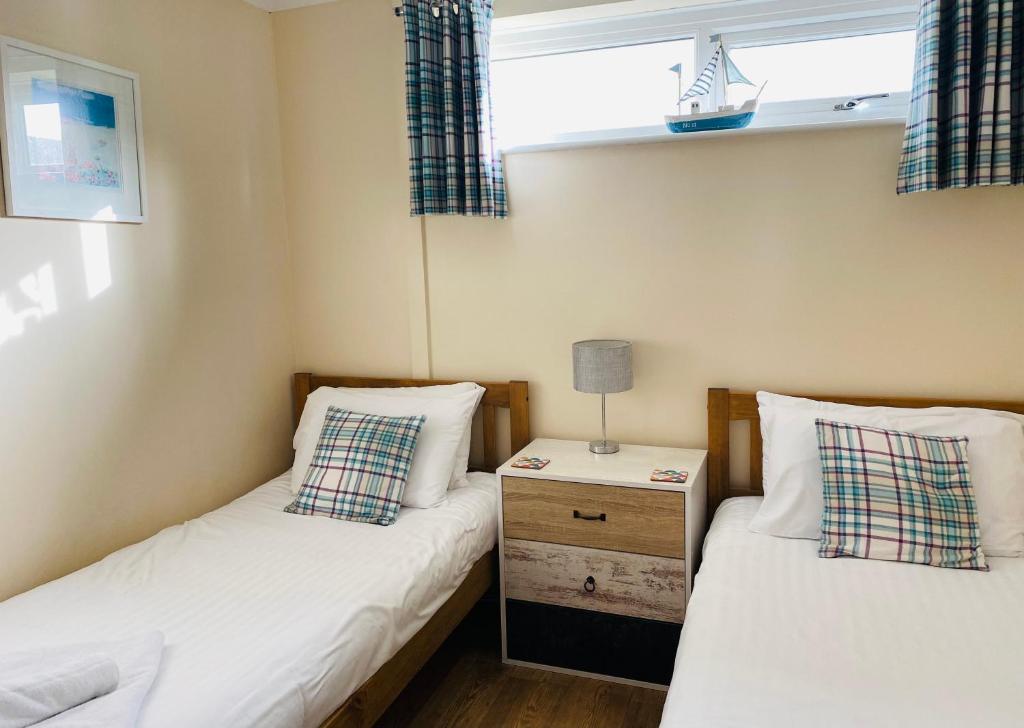 two twin beds in a small room with a night stand at Dunes View - Atlantic Bay in Perranporth