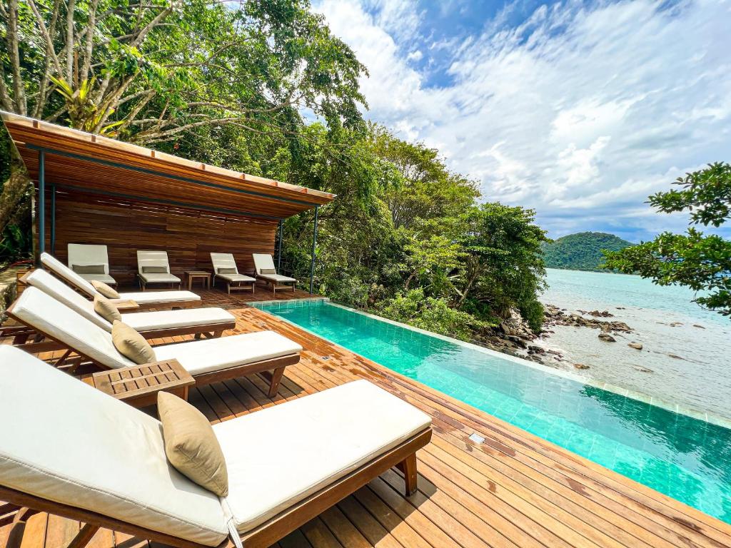 a pool on a deck next to a body of water at Casa Luz in Paraty