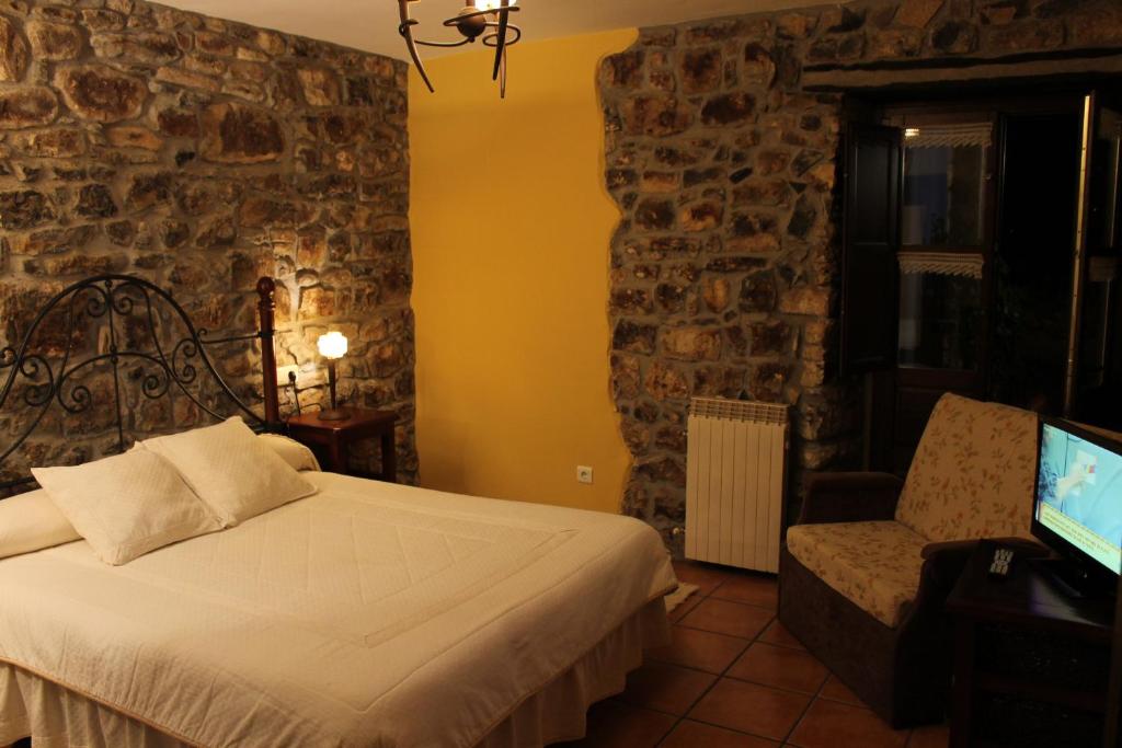 a bedroom with a bed and a chair and a tv at Rodiles Rural Apartamentos in Selorio