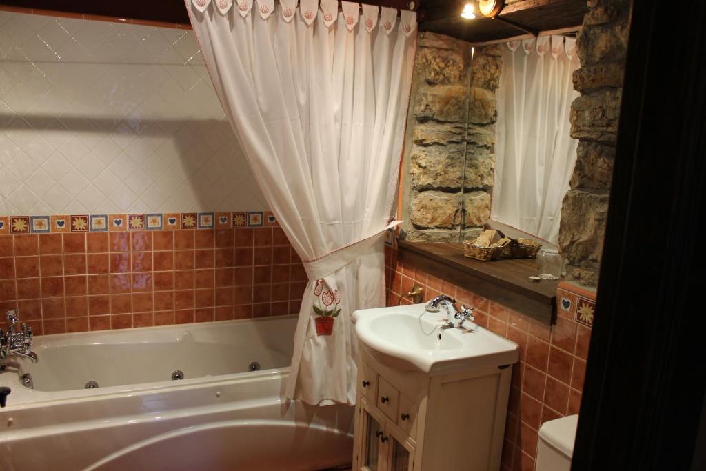 a bathroom with a tub and a sink and a bath tub at Rodiles Rural Apartamentos in Selorio