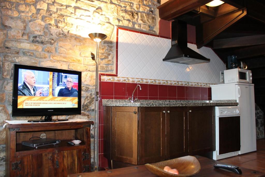 a kitchen with a flat screen tv on a counter at Rodiles Rural Apartamentos in Selorio