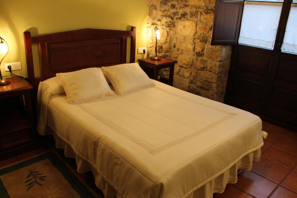 a bedroom with a large bed with two night stands at Rodiles Rural Apartamentos in Selorio