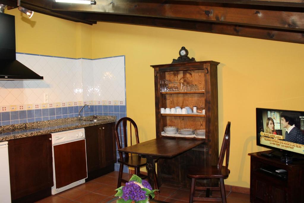 a kitchen with a table and a cabinet with dishes at Rodiles Rural Apartamentos in Selorio