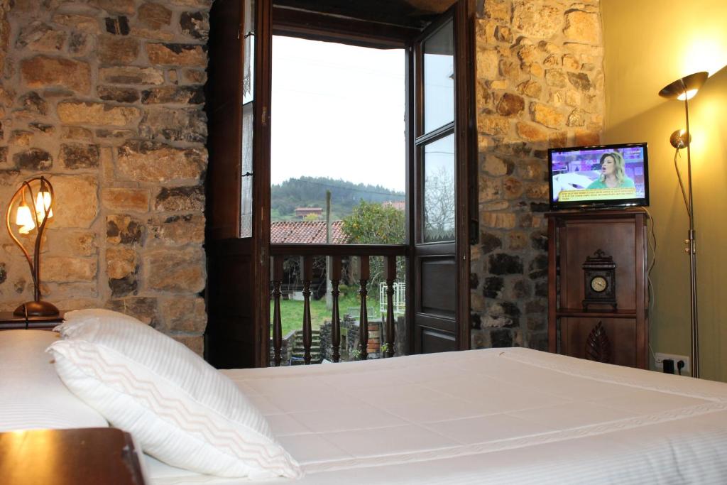 a bedroom with a bed and a window with a television at Rodiles Rural Apartamentos in Selorio