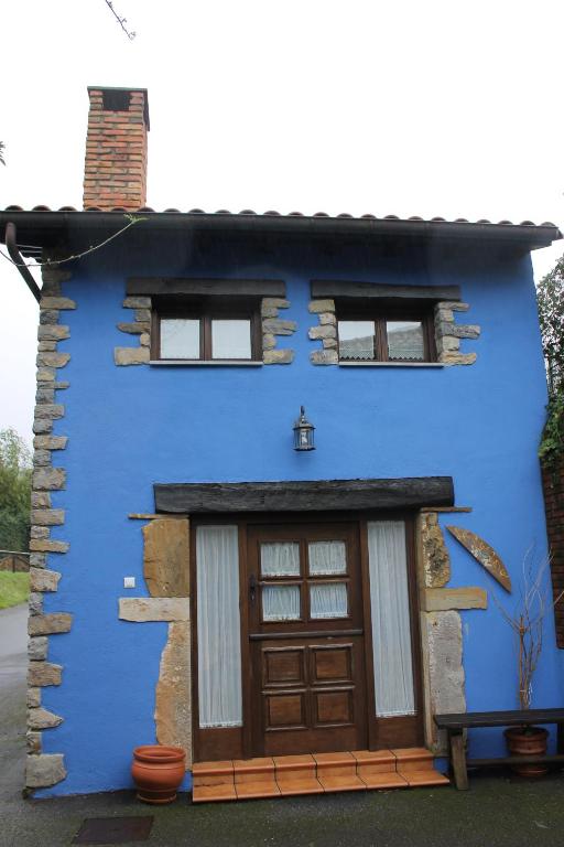 a blue house with a large wooden door at Rodiles Rural Apartamentos in Selorio