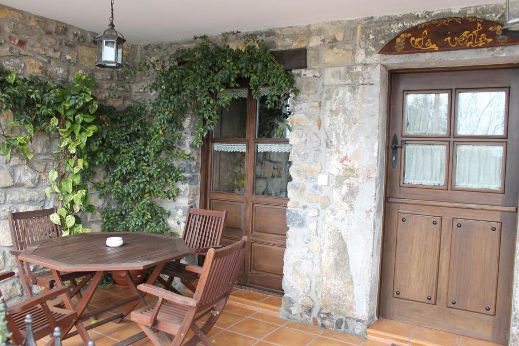 a wooden table and chairs next to a stone wall at Rodiles Rural Apartamentos in Selorio