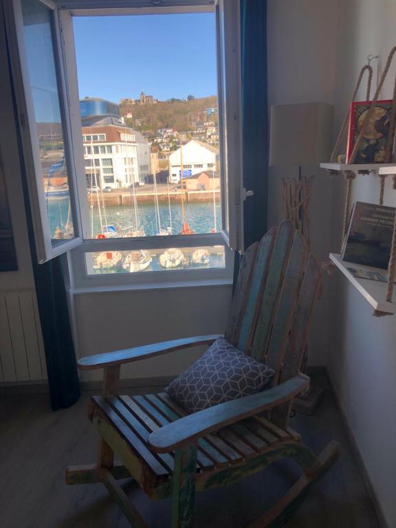 una sedia a dondolo in legno seduta di fronte a una finestra di Captain YOO - Pieds dans l’eau - Face au port a Fécamp