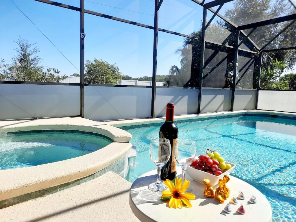 a table with a bottle of wine and fruit next to a swimming pool at Best Paradise Orlando in Orlando